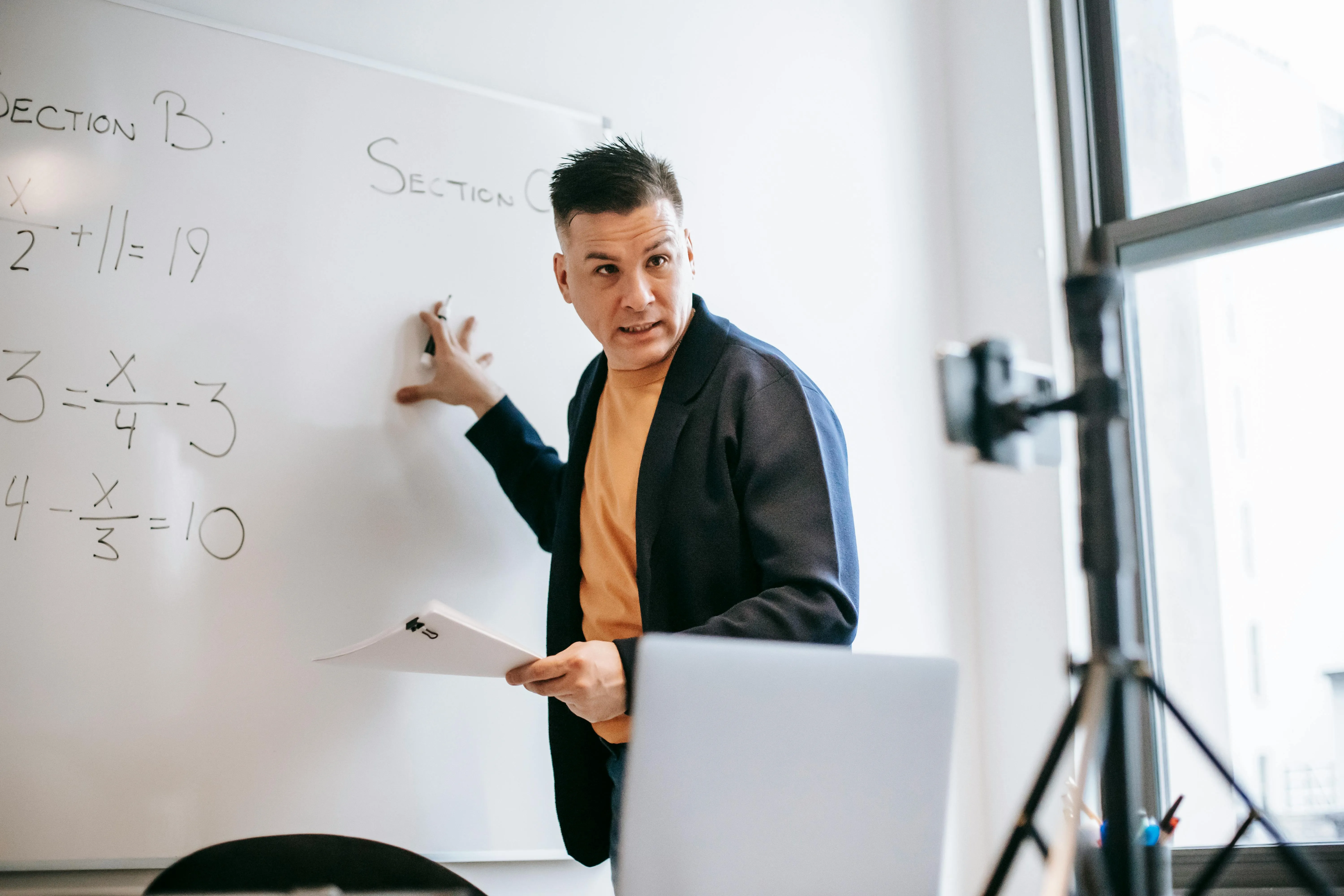 A math teacher showing off his work on a white board